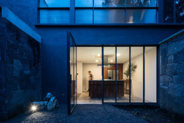 Fachada interior de Casa Estudio Chimalistac muro color gris y vista a la cosina con detalles de madera oscura