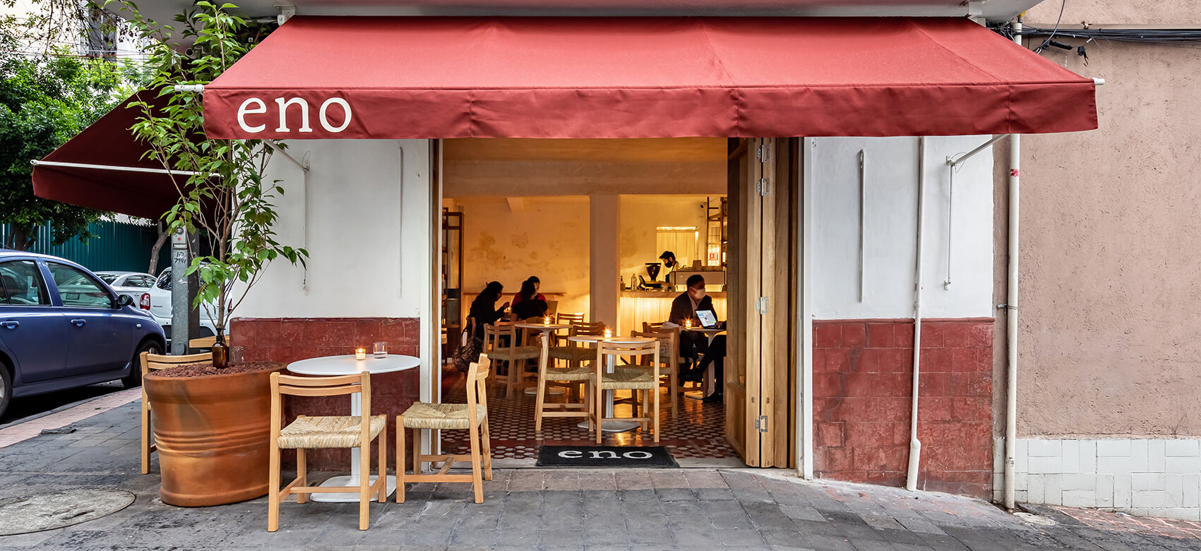Entrada principal a Eno Toki, con una fachada blanca y roja acompañado de mesas para los clientes