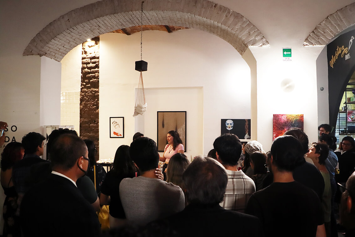 Plática de Camila Barba, rodeado de gente y piezas artísticas realizadas por ella