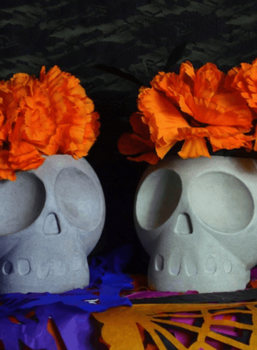 Macetas blancas con forma de calavera, adornados en un mantel de colores