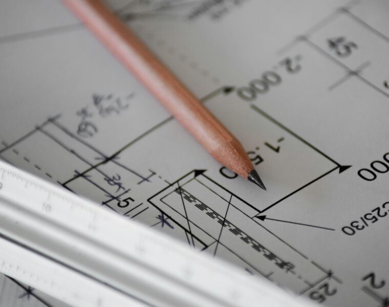 Lápiz de dibujo y reglas de escalas arquitectónicas sobre plano de casa