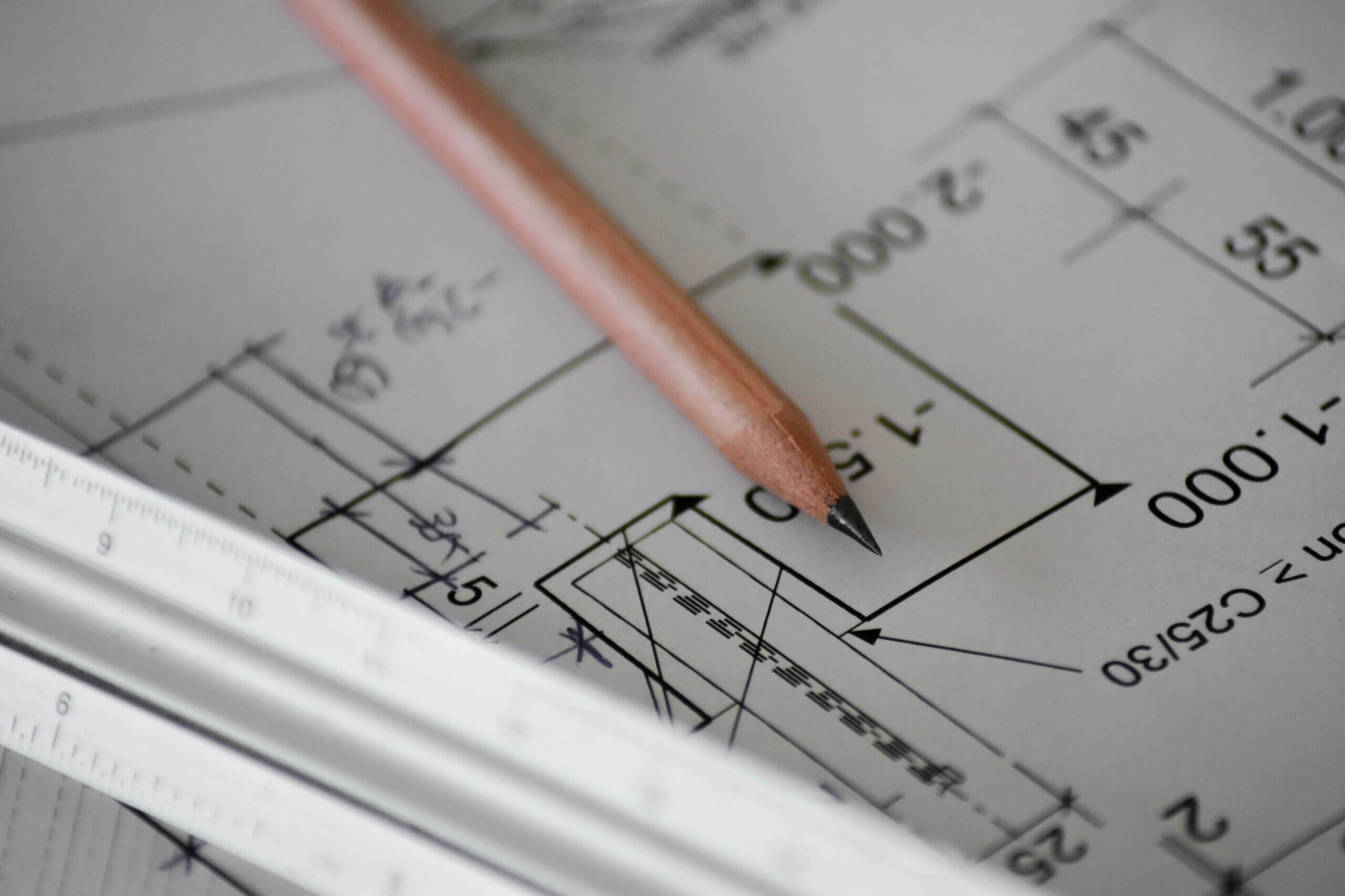 Lápiz de dibujo y reglas de escalas arquitectónicas sobre plano de casa